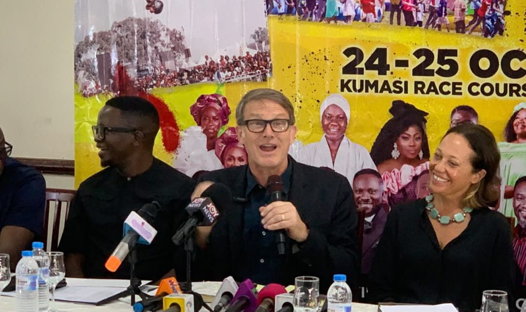 Evangelist Andrew Palau speaking at the Love Ghana Festival press conference in Kumasi, with a festival banner behind the panel
